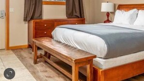 A bedroom with a wooden bed, a bench, a window with curtains, and a framed picture on the wall. - Chelan Cabana Chalet (chelan)