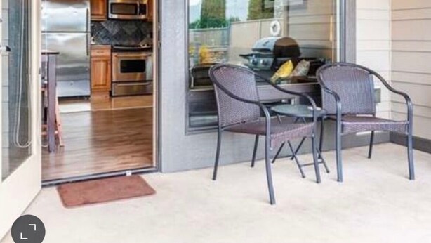 An open patio with a dining table and chairs, a glass door leading to a kitchen with stainless steel appliances, and a wooden ceiling. - Chelan Cabana Chalet (chelan)