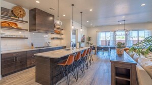 A modern kitchen with a central island, dark cabinetry, and pendant lighting.
