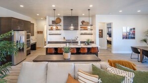 A modern kitchen with a central island, built-in appliances, and pendant lighting.