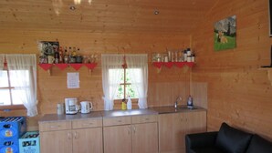 Interior de una cabaña de madera con kitchenette, comedor y sofá.