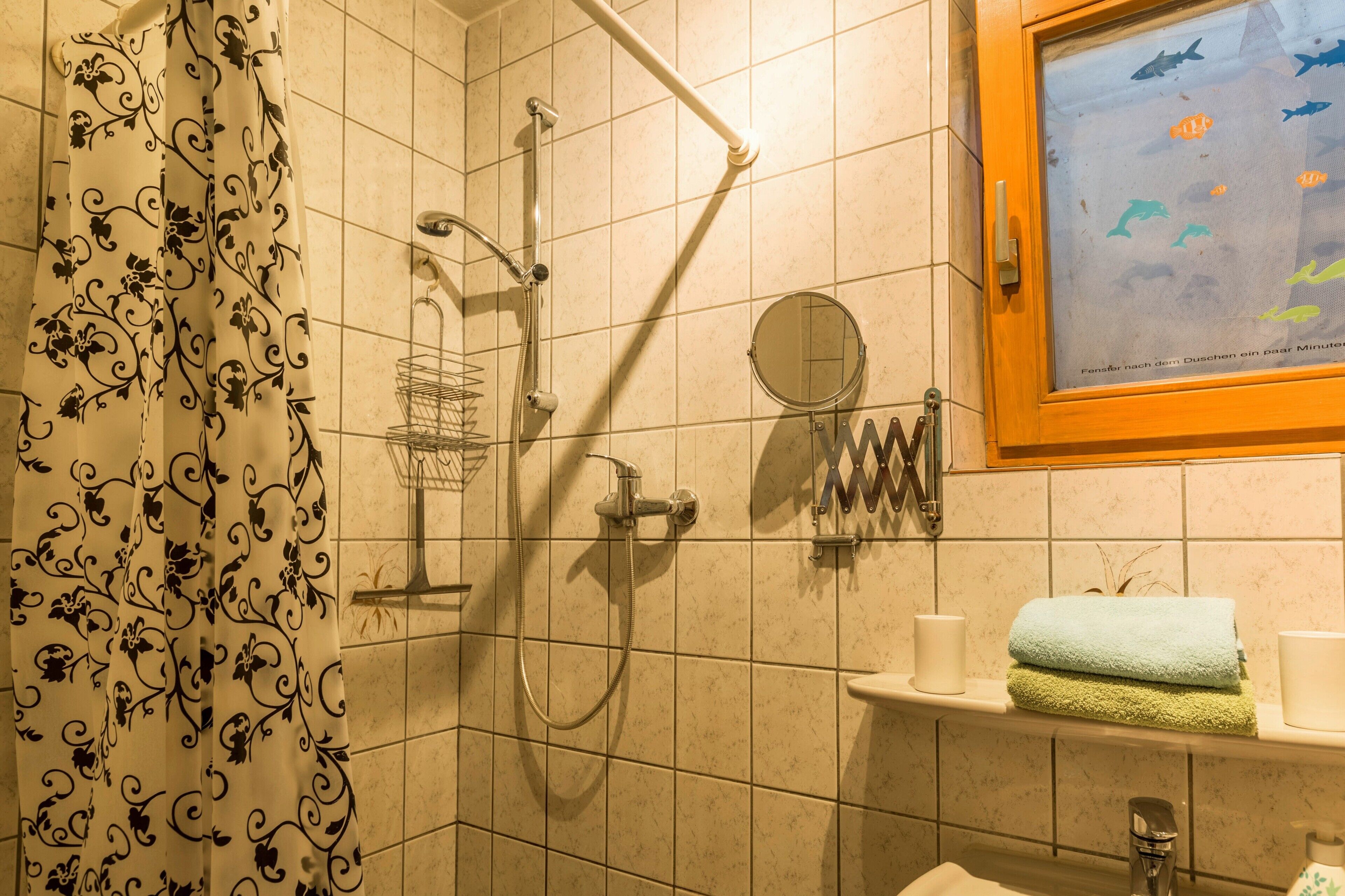 A bathroom with a shower, a towel rack, a mirror, and a framed picture on the wall.