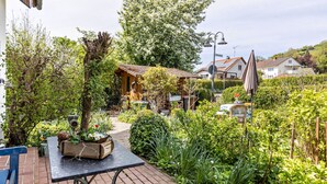 A garden with a wooden structure, a table with a plant, and a bench. - Cozy Holiday Apartment "Alina" with Garden Seating, Wi-Fi, Non-Smoking (Singen)