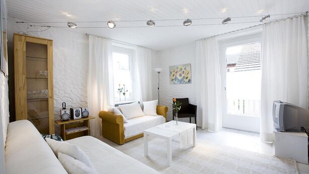 A modern, well-lit living room with a sofa, coffee table, and a television. - Charming Apartment "Bregenz 6 Top 2" with Wi-Fi, Balcony, Terrace & Garden (Bregenz)