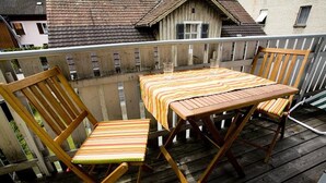 A wooden deck with a table and chairs, a railing, and a view of houses in the background. - Charming Apartment "Bregenz 6 Top 2" with Wi-Fi, Balcony, Terrace & Garden (Bregenz)