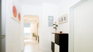 A hallway with a white wall, a black and white cabinet, a yellow rug, and a door leading to another room. - Charming Apartment "Bregenz 6 Top 2" with Wi-Fi, Balcony, Terrace & Garden (Bregenz)