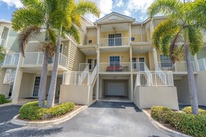 A multi-story residential building with balconies, a garage, and palm trees. - Fantastic Water Views | Newly Updated 3 Bed Town Home | Pet friendly | Sleeps 8 (Ruskin)