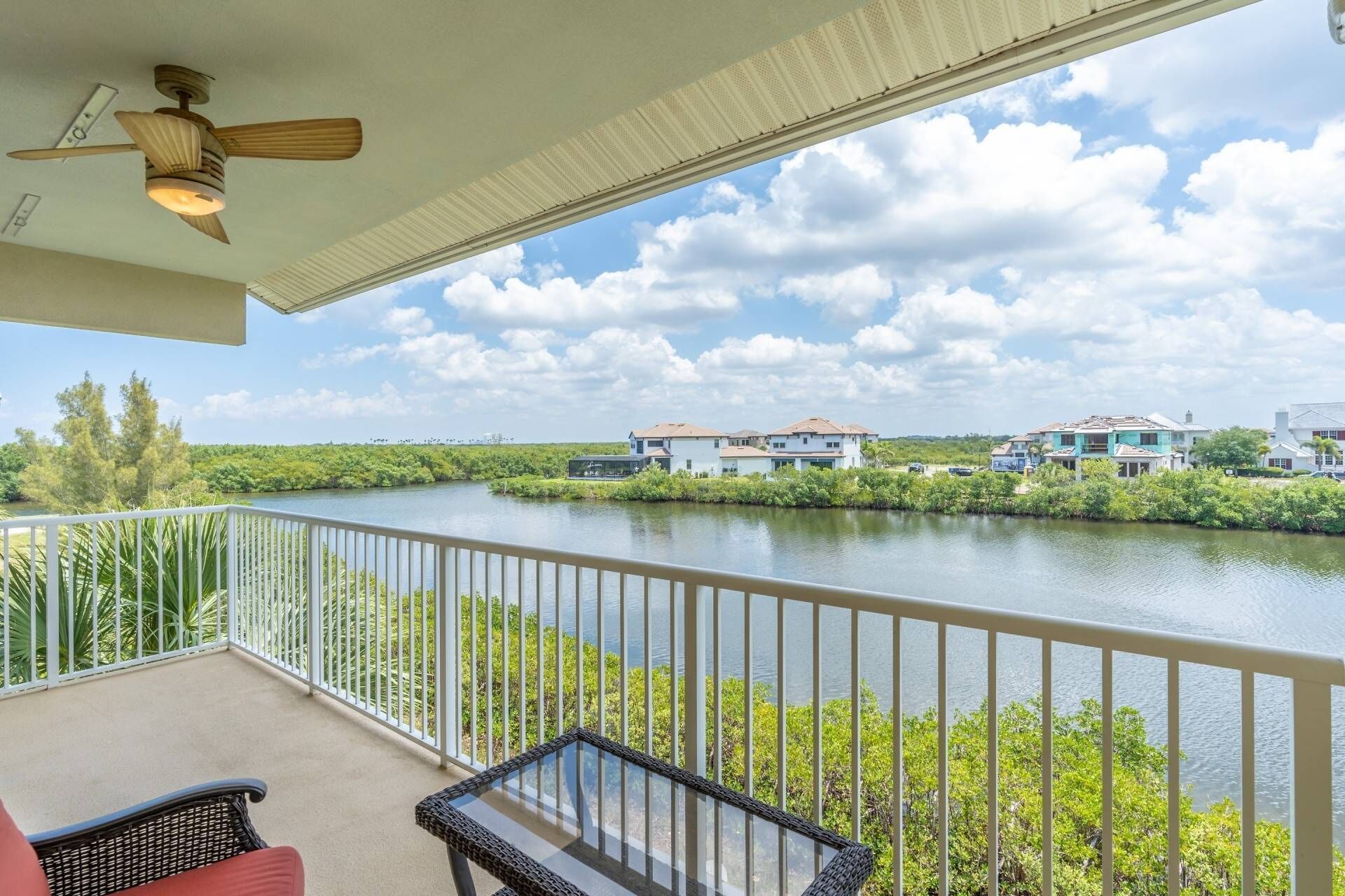 A balcony with a view of a river, a ceiling fan, and a railing.