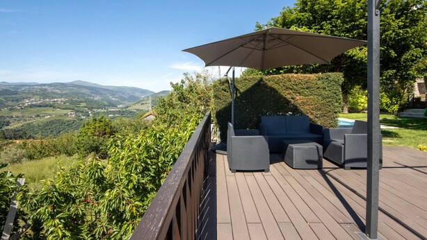 A deck with outdoor furniture and a large umbrella, overlooking a scenic landscape. - Holiday Home Casa do Valado with Mountain View, Pool, Wi-Fi & Garden; Parking Available (Resende)