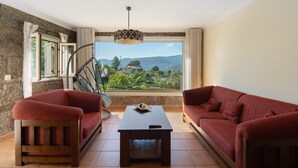 A room with a sofa, a chair, a table, and a view of a mountainous landscape. - Holiday Home Casa do Valado with Mountain View, Pool, Wi-Fi & Garden; Parking Available (Resende)