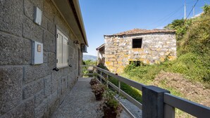 A stone building with a tiled roof, a balcony with potted plants, and a white railing. - Holiday Home Casa do Valado with Mountain View, Pool, Wi-Fi & Garden; Parking Available (Resende)