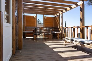 Eine Holzterrasse mit Tisch, Stühlen und einer Bank, mit Blick ins Freie.