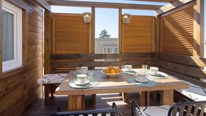 A wooden deck with a table set for four, including cups, saucers, and a bowl of fruit. - Cabana Garden House with Shared Pool, Panoramic View & Wi-Fi (Loulé)