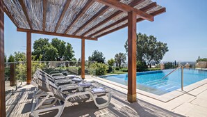A poolside area with lounge chairs, a pergola, and a view of the pool and surrounding greenery. - Cabana Garden House with Shared Pool, Panoramic View & Wi-Fi (Loulé)