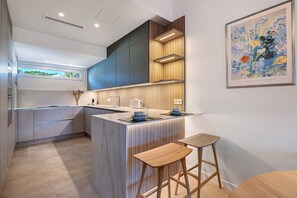 Een moderne keuken met een centraal eiland, houten accenten en een gekaderd kunstwerk aan de muur.