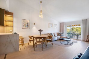 Un espacio habitable moderno con una isla de cocina de mármol, muebles de madera y una zona de comedor.
