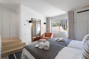 Una habitación de hotel con una cama, una silla, un ventanal y una escalera.
