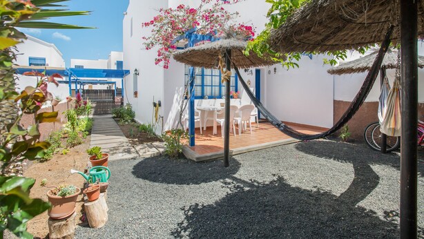A courtyard with a thatched roof, potted plants, and a white building with blue accents. - Vacation Home 'Rosa' with Private Terrace, Private Garden and Wi-Fi (Yaiza)