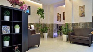 Un vestíbulo moderno con una mesa de recepción, un sofá y plantas en macetas.