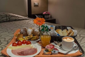 A breakfast tray with pastries, bread, a plate of meats and cheese, tomatoes, and a cup of coffee. - Catone District Hotel (Rome)