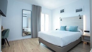 A modern hotel room with a large bed, a desk, and a chair. - Hotel Evenia Coral (Torroella de Montgrí)