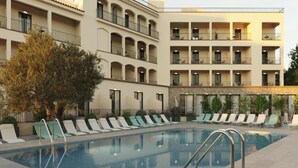 A pool area with lounge chairs and a building with multiple balconies. - Hotel Evenia Coral (Torroella de Montgrí)