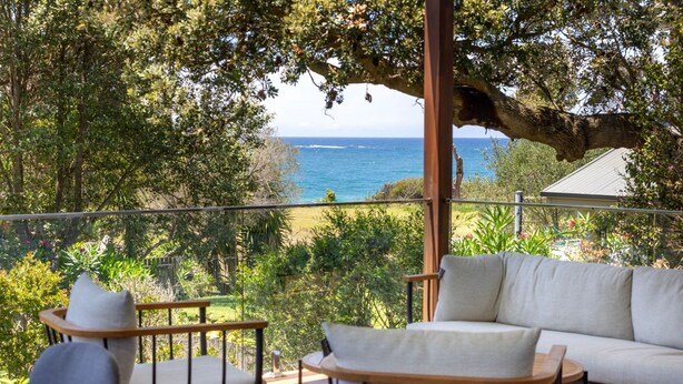 Un balcone con vista sul mare, un divano e una poltrona.