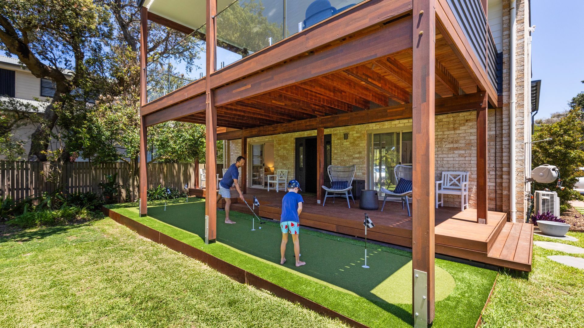 A modern house with a covered patio area, a small lawn, and a brick exterior.