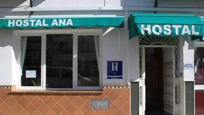 A building with a sign reading "HOSTAL ANA" and a blue sign with an 'H' indicating a hostel.