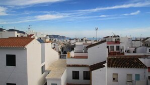 Una zona residencial costera con edificios blancos y tejados de tejas rojas, bajo un cielo azul despejado.