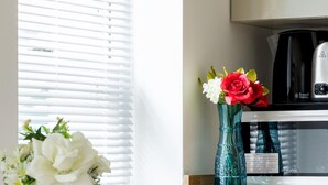 A dining area with a table set for two, a vase with flowers, and a coffee maker on the counter. - Duplex Apartment With Patio in Marylebone (London)