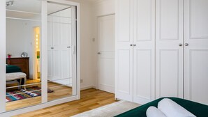 A bedroom with a large wardrobe, a bed with a green bedspread, and a mirror cabinet. - Duplex Apartment With Patio in Marylebone (London)