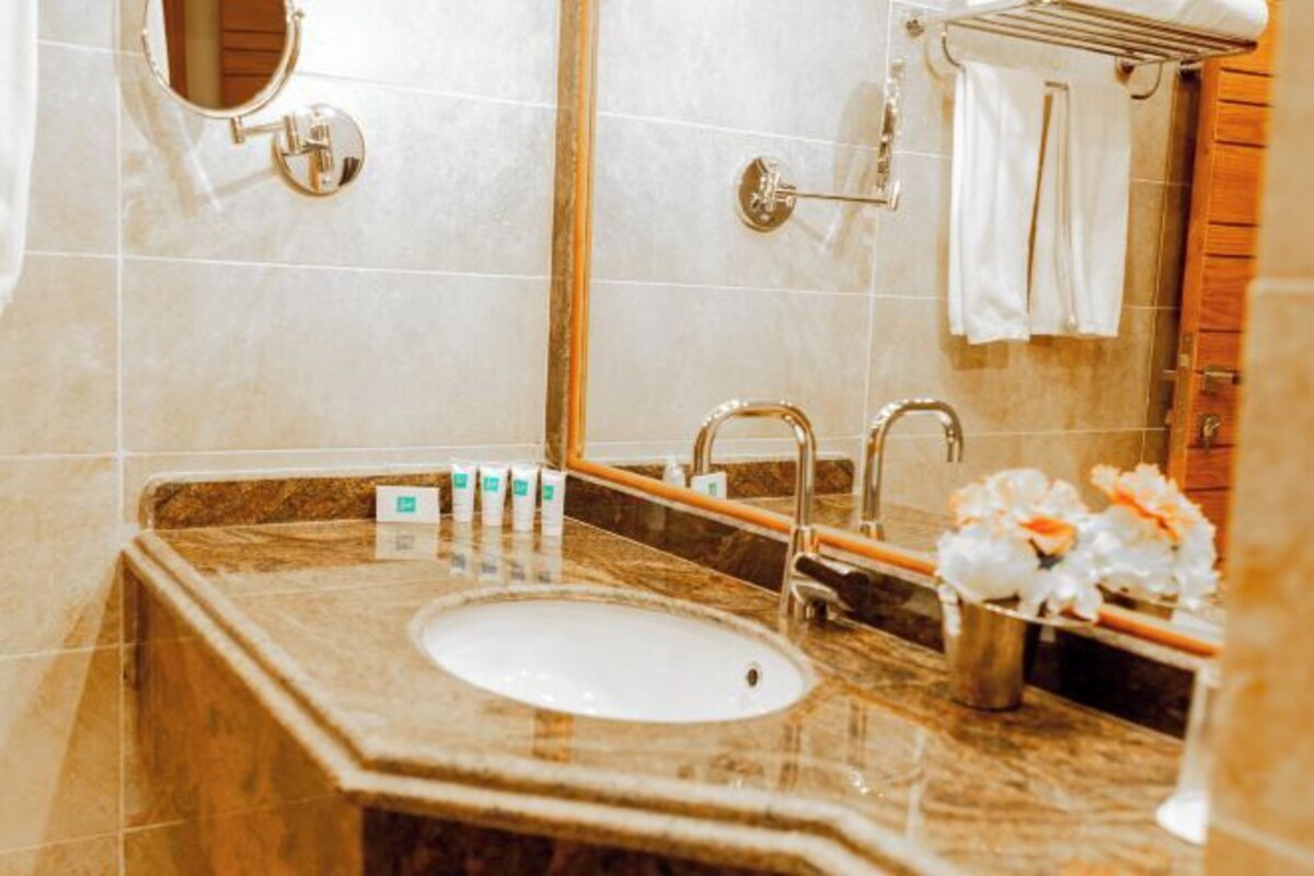 A bathroom with a marble sink, a mirror, a towel rack, and toiletries on the counter.