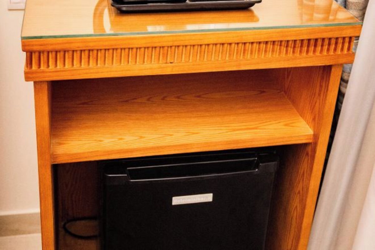A wooden cabinet with a glass top and a black appliance inside.