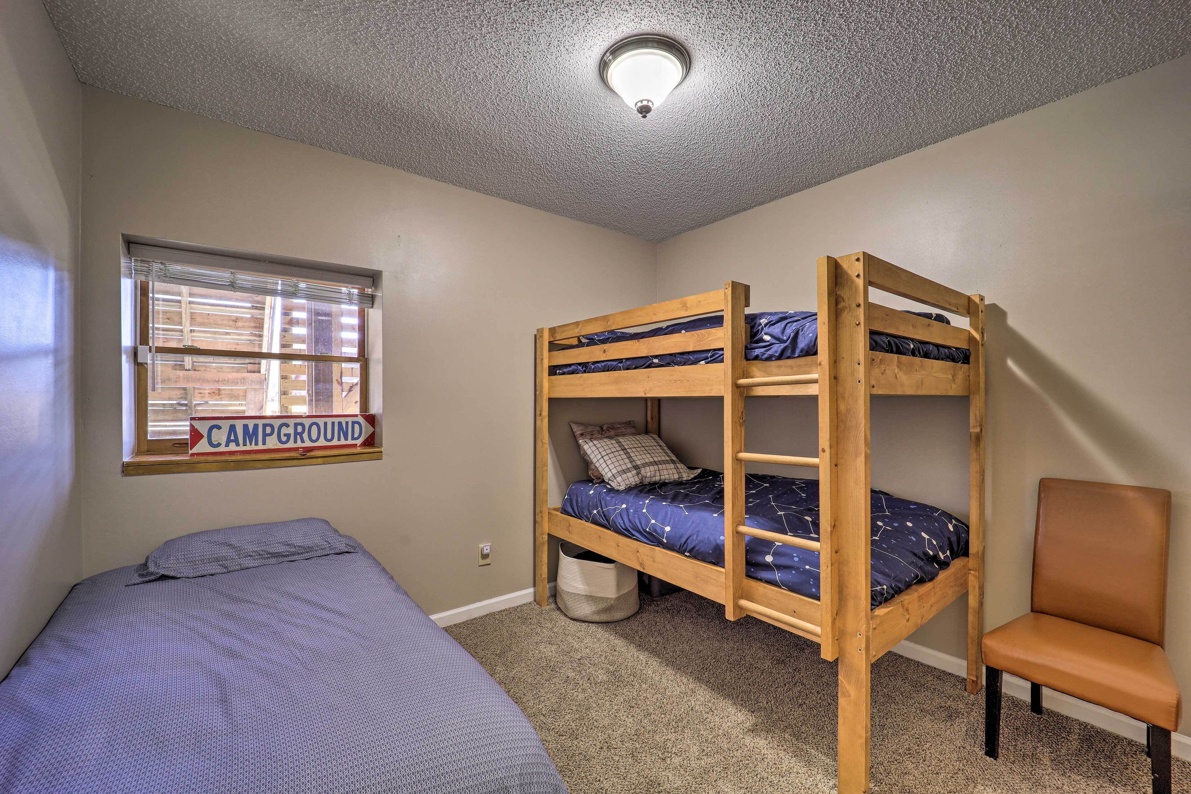 A bunk bed room with a window labeled "CAMPGROUND" and a chair.
