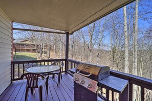 A covered outdoor deck with a grill and seating area, overlooking a wooded area. - Walk to New River Access! Family Cabin w/ Deck (Piney Creek)