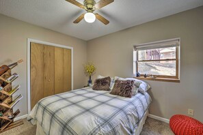 Ein Schlafzimmer mit einem Bett, einem Holzschrank, einem Fenster und einem Deckenventilator.