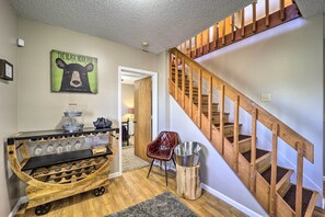 Una escalera de madera con barandilla, un letrero en la pared que dice 'THE BLACK BEAR PUB' y un carrito de bar con vasos y botellas.