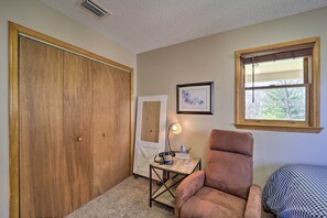 Una habitación con un armario de madera grande, un escritorio con lámpara, una silla y una ventana con persianas.