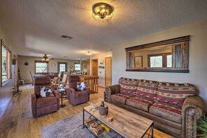 A spacious living room with a wooden floor, leather sofas, a coffee table, and a large mirror on the wall. - Walk to New River Access! Family Cabin w/ Deck (Piney Creek)