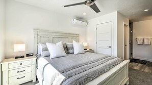 A bedroom with a bed, nightstands, a ceiling fan, an air conditioning unit, and a door. - Spacious St. George Townhome w/ Grill & Views! (St. George)