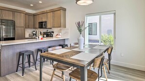 A modern kitchen with wooden cabinets, a stainless steel refrigerator, and a large island with bar stools. - Spacious St. George Townhome w/ Grill & Views! (St. George)