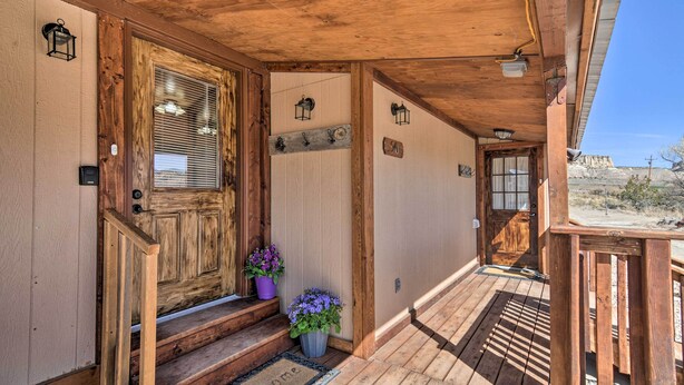 A wooden porch with a wooden door, potted plants, and a welcome mat. - Cozy Home w/ Canyon Views: 2 Mi to Grand Staircase (Henrieville)