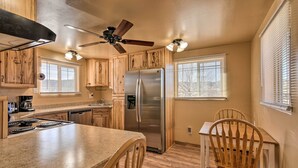 A kitchen with wooden cabinets, a stainless steel refrigerator, a ceiling fan, and a dining area with wooden chairs. - Cozy Home w/ Canyon Views: 2 Mi to Grand Staircase (Henrieville)