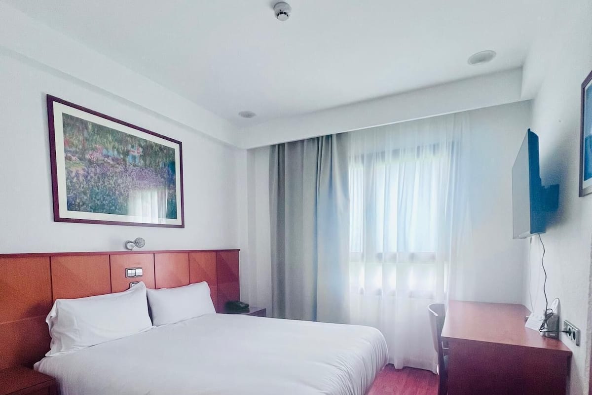 Une chambre d’hôtel avec un grand lit, un bureau et une chaise.