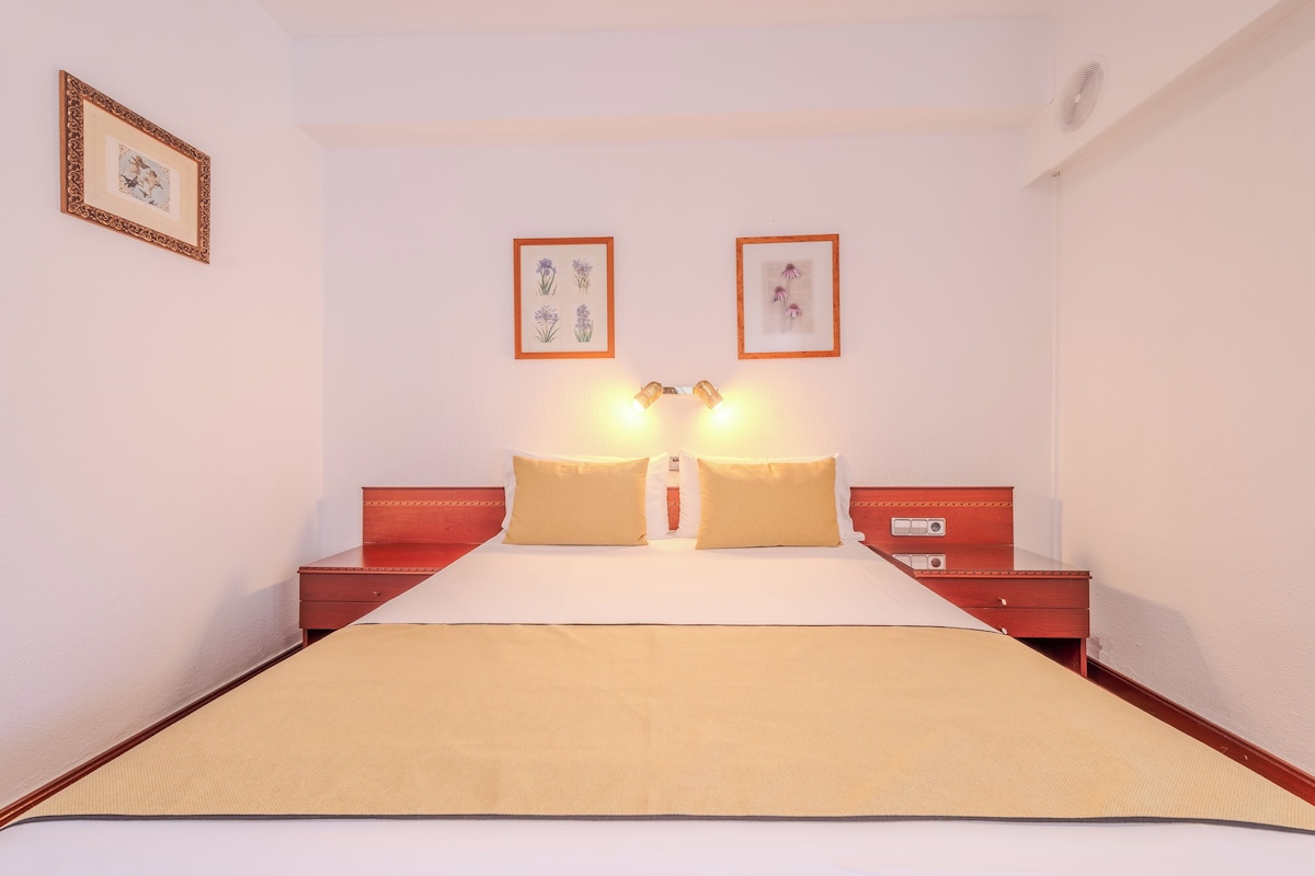 Une chambre d’hôtel avec un grand lit, deux tables de chevet et des œuvres d’art accrochées au mur.