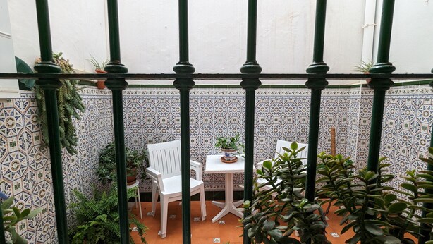 A small patio with a white table and chairs, surrounded by potted plants and a tiled wall. - Casa Marialuisa - Casa original en el Casco antiguo (Barbate)