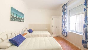 A room with two beds, a wardrobe, a painting, and a window with curtains. - Casa Marialuisa - Casa original en el Casco antiguo (Barbate)