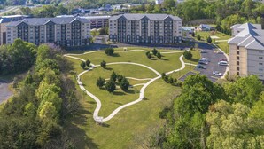 En flervåningsbostadsbyggnad med en central innergård, parkeringsplats och omgivande grönska.