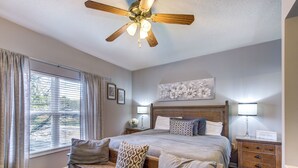 A bedroom with a bed, bedside tables, a ceiling fan, and a window with curtains.